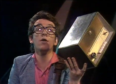 Elvis Costello holds up a Radio Radio